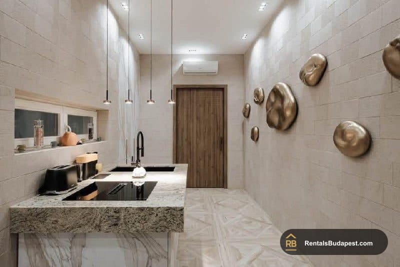 Galley kitchen with granite island, black induction hob, pendant lights, and gold sculptural discs on the wall