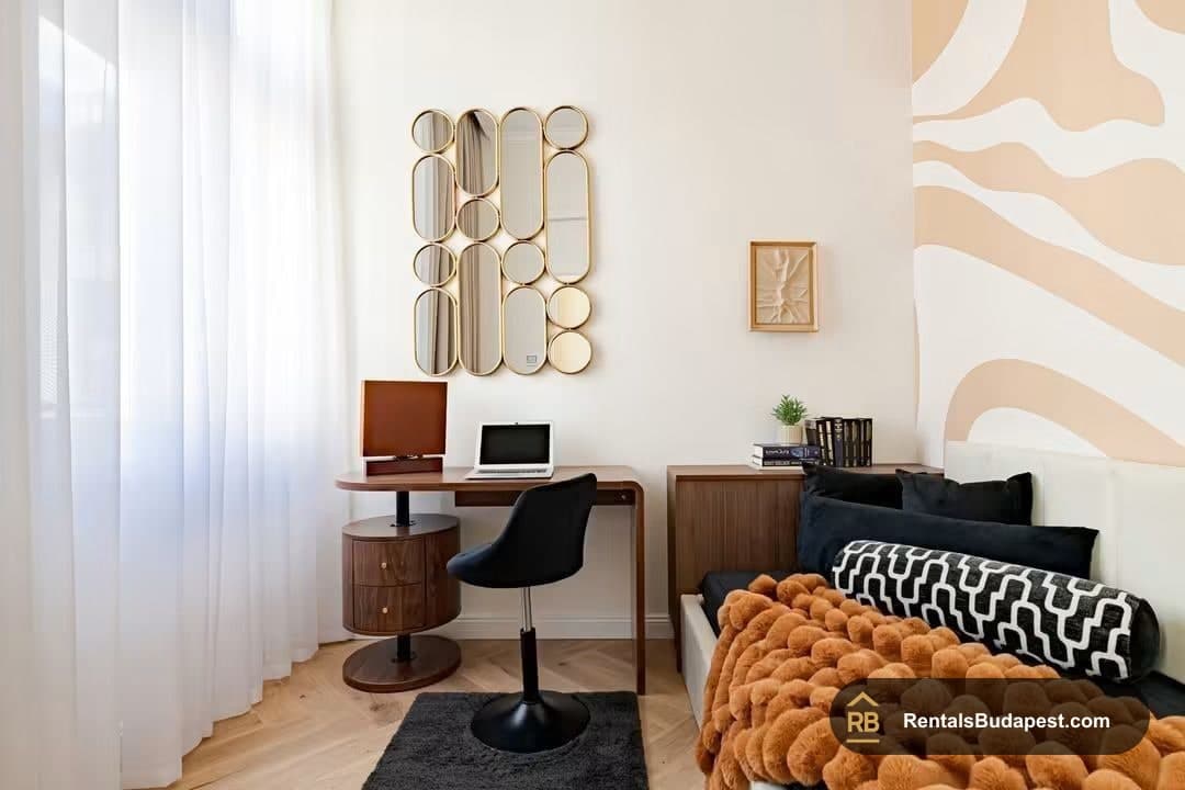 Compact bedroom with walnut desk, round mirror panels, orange throw on bed, Falk Miksa utca