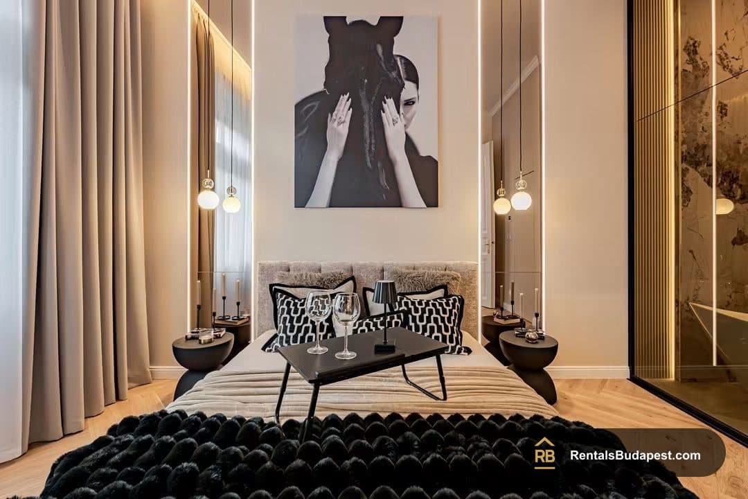 Bedroom with monochrome portrait above bed, black fur throw and glowing pendant lamps, Falk Miksa utca