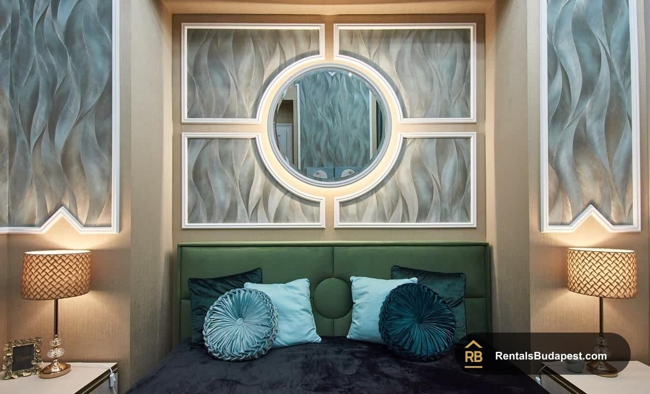 Bedroom detail with green headboard, teal cushions and backlit round mirror, Szent István körút