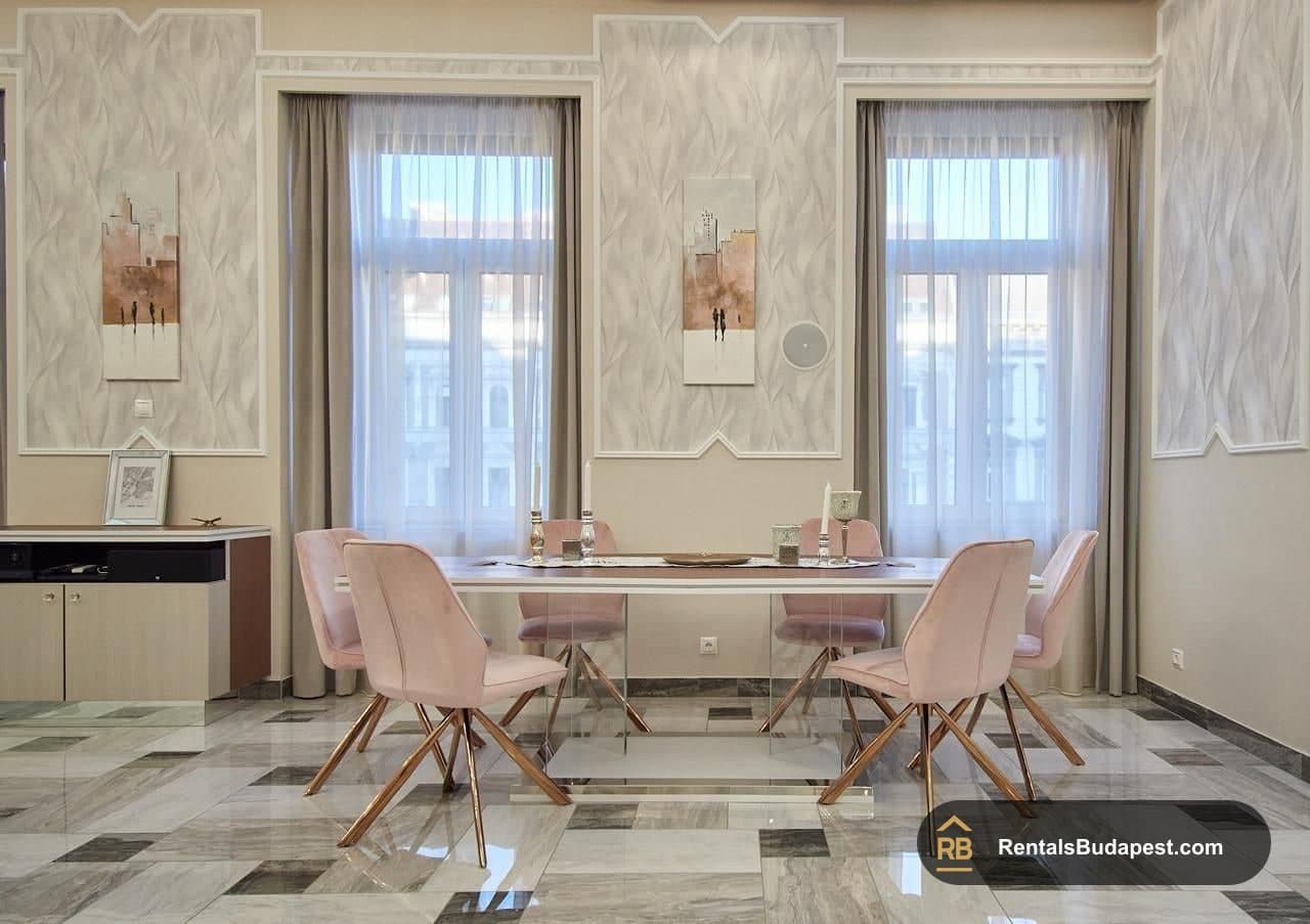 Dining area with pink velvet chairs, glass table and tall windows with sheer curtains