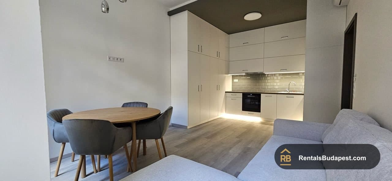Dining corner with round wooden table, grey chairs, and kitchen cabinets with under-cabinet lighting