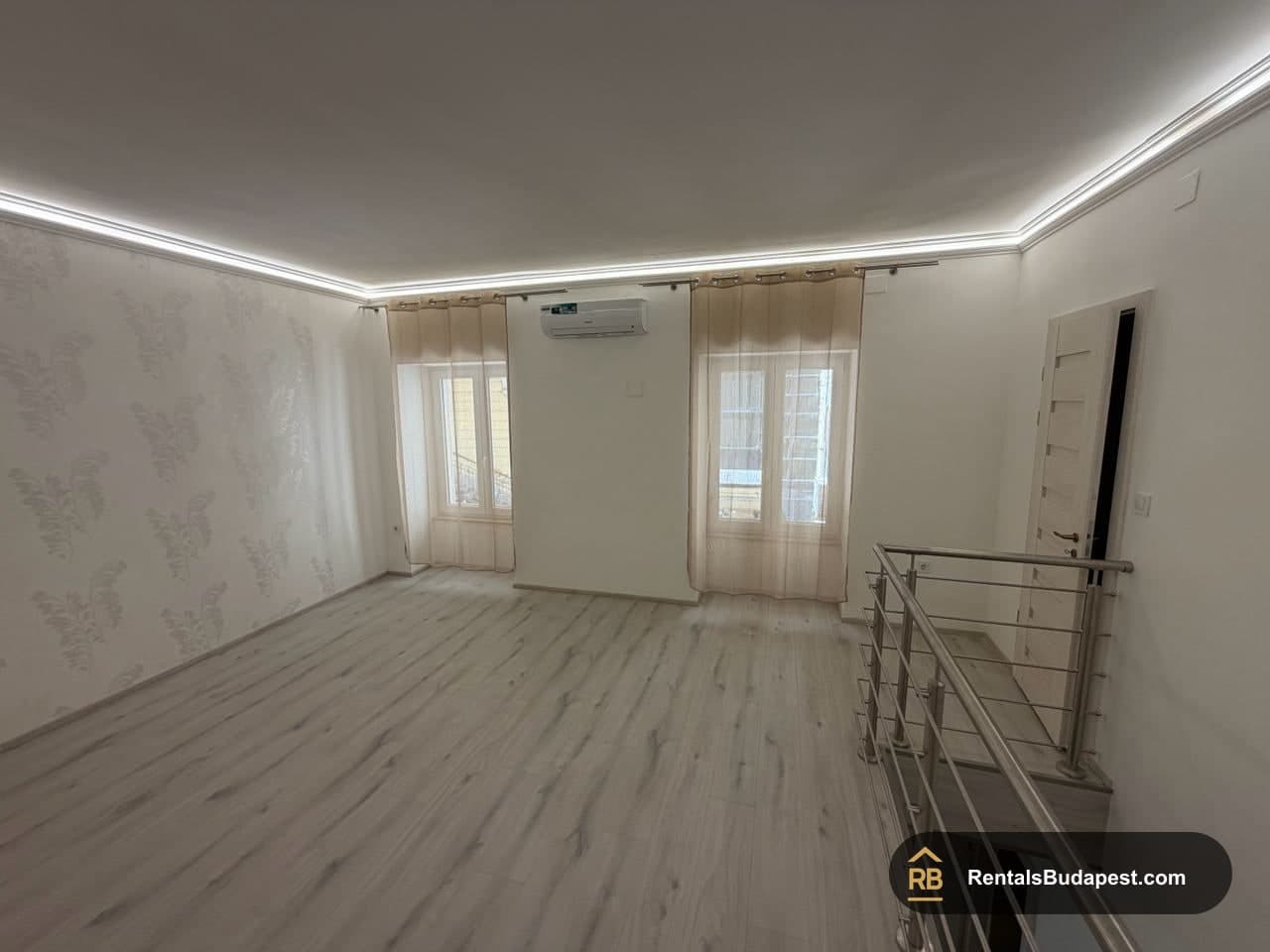 Bright upper-level room with wood-effect laminate floors, wall air conditioner and steel balcony railing, Szent István körút