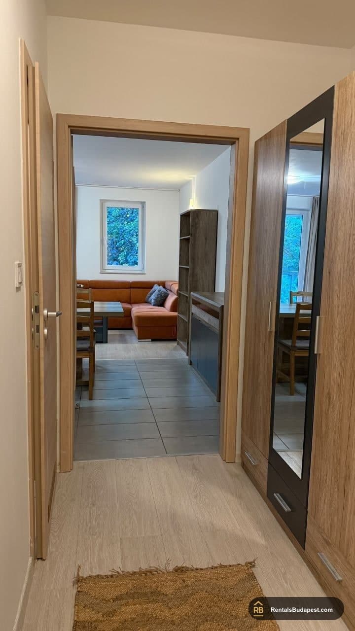 Hallway with mirrored wardrobe, looking through to orange sofa in living room, Viola utca