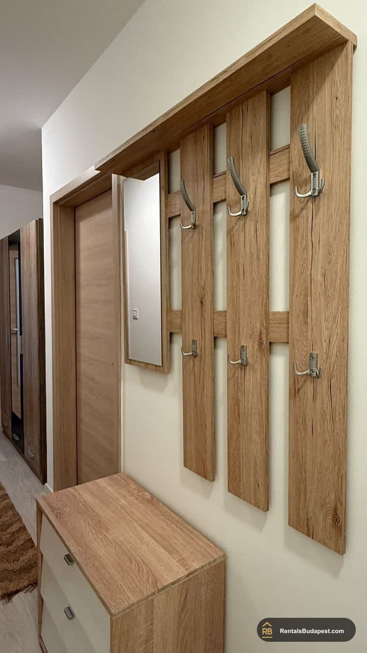 Oak wall coat rack with three hooks and a mirror beside a wooden shoe cabinet in a hallway, Viola utca